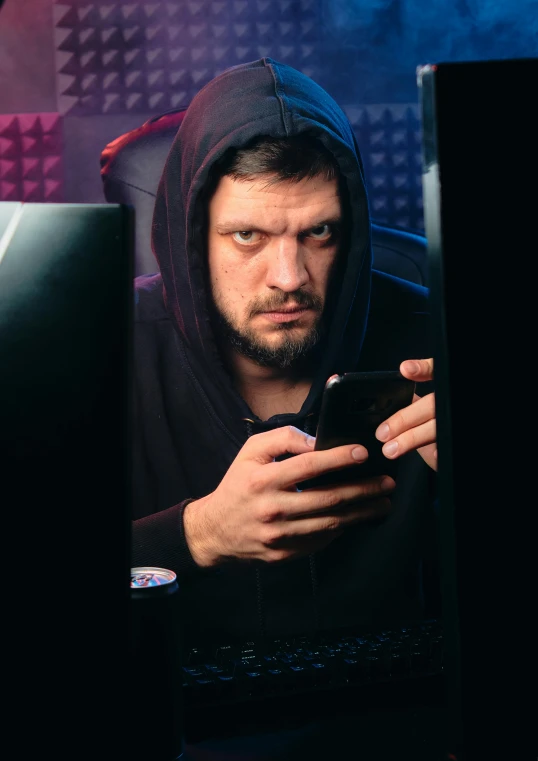 a man in a hoodie looking at a cell phone, a portrait, trending on reddit, gaming pc, 🔥 😎 🕹️ 👀 :2, staring hungrily, dark photo