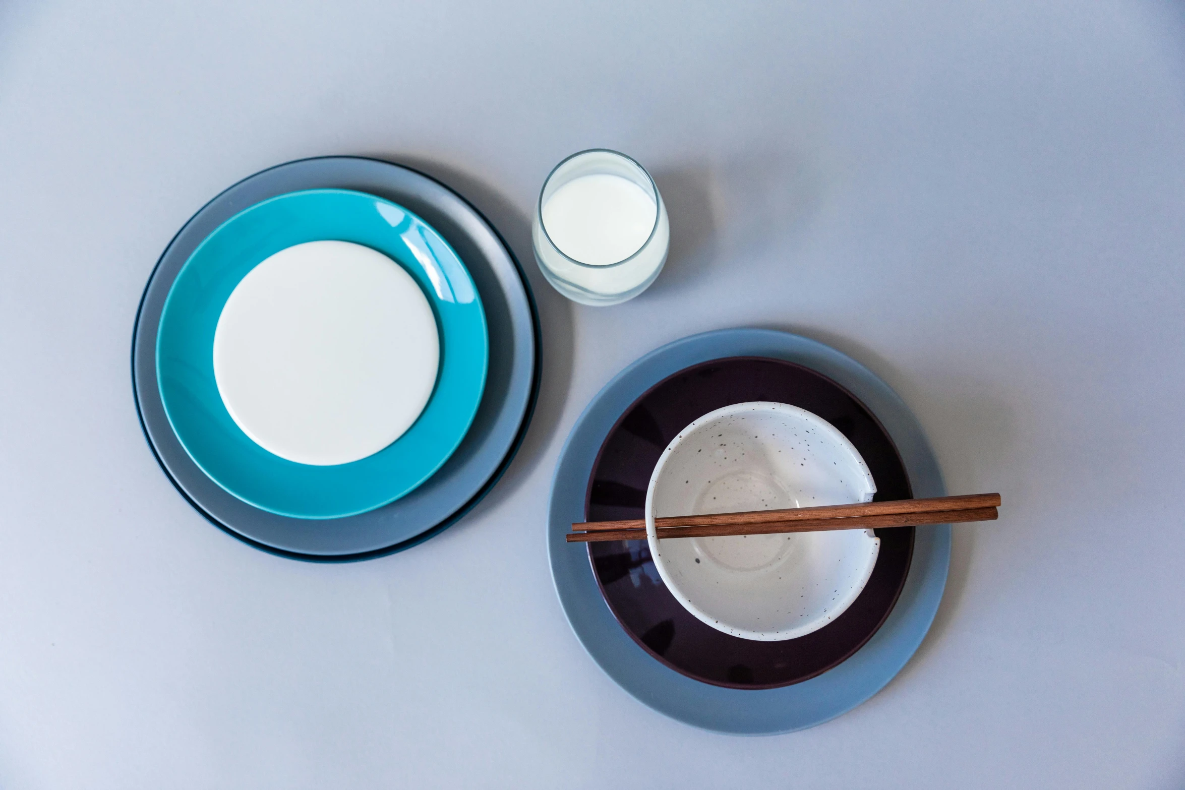 a table topped with plates and chopsticks next to a glass of milk, inspired by Doug Ohlson, instagram, minimalism, brown and cyan blue color scheme, mauve and cinnabar and cyan, 3 - piece, opaque glass