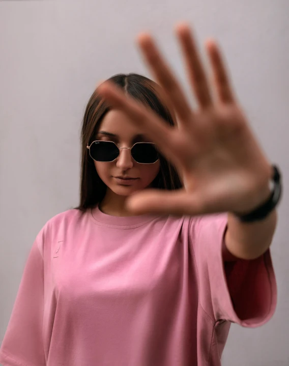 a woman is making a stop sign with her hands, trending on unsplash, wearing shades, portrait of a pink gang, low quality photo, nonbinary model