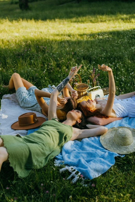a group of people laying on a blanket in the grass, cottagecore, wining, hot weather, playing