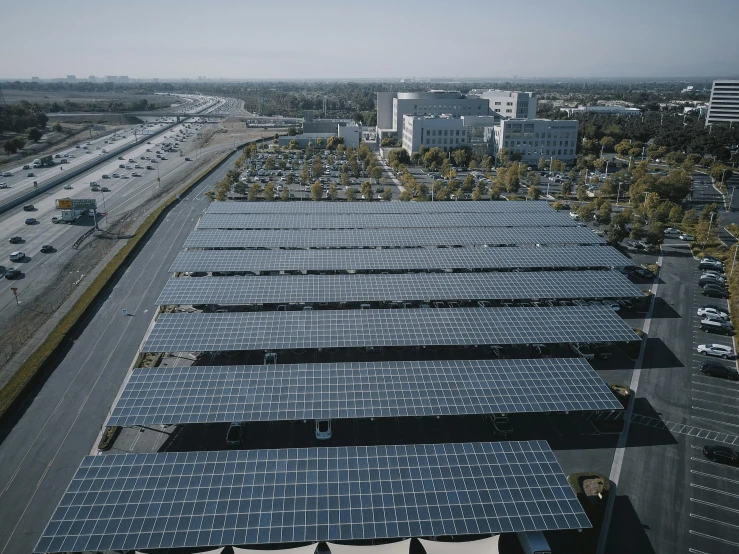 a large array of solar panels on the roof of a building, by Carey Morris, unsplash, parking lot, aerial footage, square, cinematic image