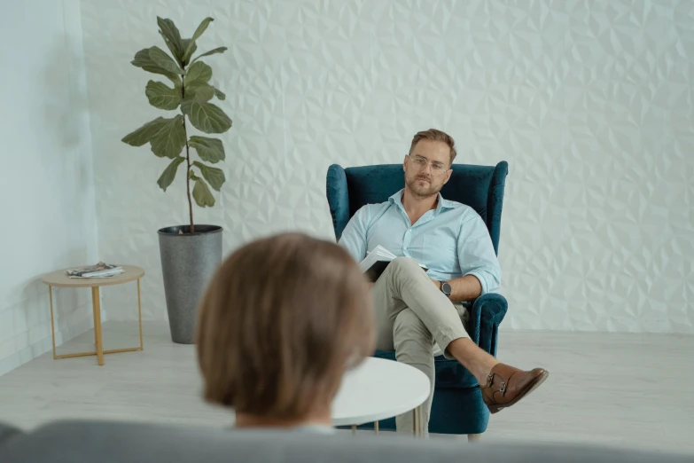 a man sitting in a chair in a living room, looking at each other mindlessly, doctors office, central hub, profile image