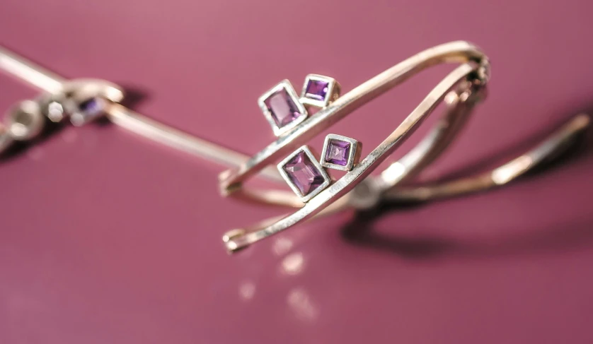 a couple of rings sitting on top of a table, by Emma Andijewska, trending on pexels, crystal cubism, purple tubes, garnet, squares, vine twist