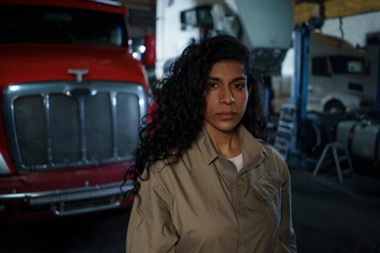 a woman standing in front of a red truck, a portrait, by Jeffrey Smith, pexels contest winner, serial art, from netflix's arcane, wearing prison jumpsuit, karla ortiz, in a warehouse