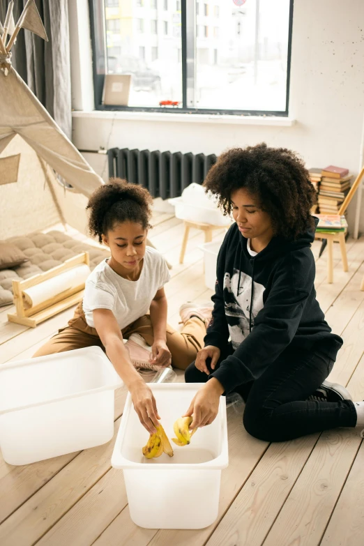 a woman and a child are sitting on the floor, pexels contest winner, process art, looking at the treasure box, white and yellow scheme, apartment, varying ethnicities