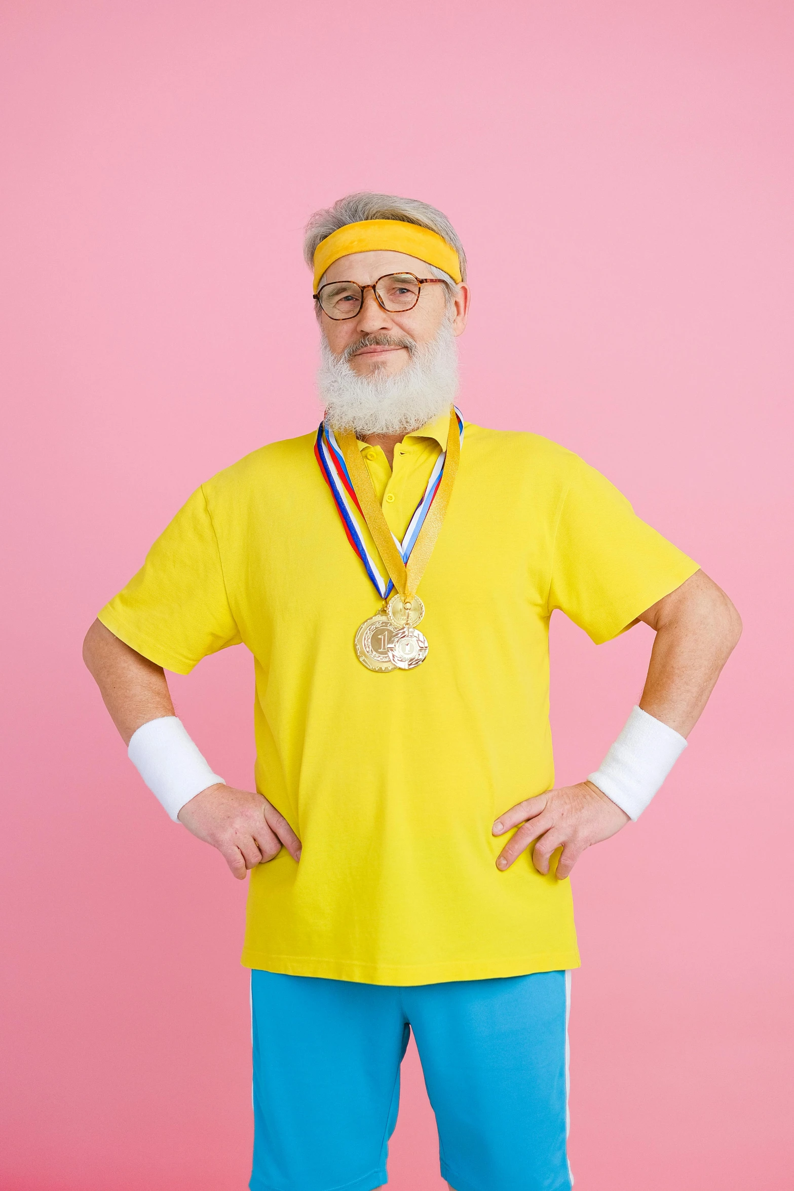 a man in a yellow shirt and blue pants with a medal around his neck, inspired by Dong Kingman, pexels contest winner, full white beard, wearing a pink head band, wearing a volleyball jersey, blippi