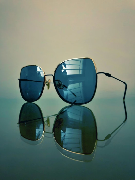 a pair of sunglasses sitting on top of a table, a picture, by Andrei Kolkoutine, unsplash, photorealism, black gold light blue, cinematic. by leng jun, beautiful reflexions, square glasses