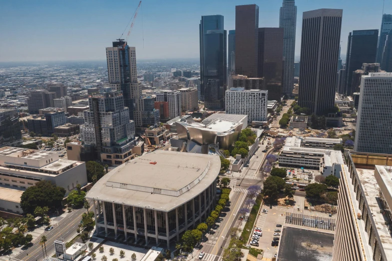 an aerial view of a city with tall buildings, an album cover, inspired by L. A. Ring, unsplash contest winner, dodgers stadium concert in 1975, wide angle exterior 2022, brutalist architecture buildings, full of people