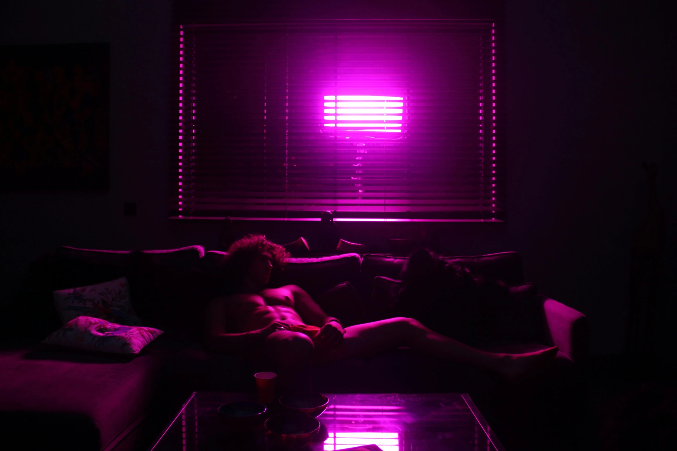 a person laying on a couch in a dark room, inspired by Nan Goldin, massurrealism, bright pink purple lights, synthwave image, rgb wall light, window lights