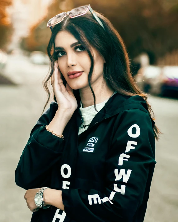 a woman standing on a street talking on a cell phone, trending on pexels, mia khalifa, wearing a hoody, frown fashion model, black bomber jacket