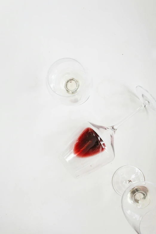 a couple of wine glasses sitting on top of a table, inspired by Anish Kapoor, process art, flatlay, bloody, on white, up close