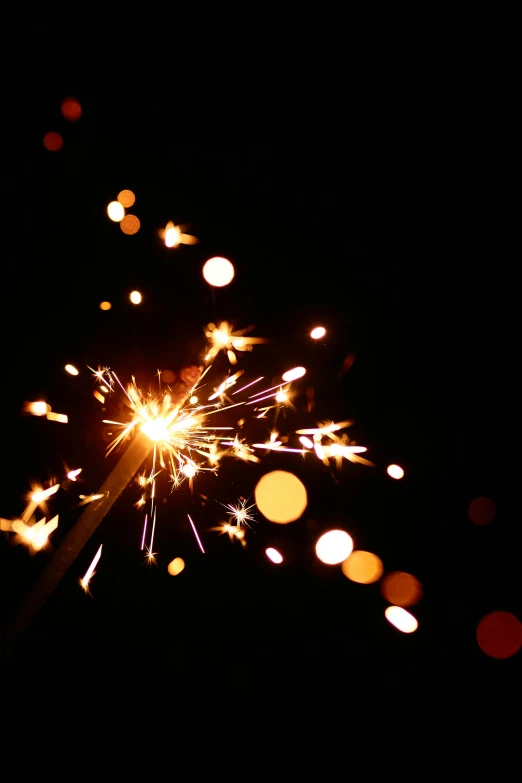 a close up of a sparkler in the dark, pexels, shining gold and black and red, in 2 0 1 2, confetti, and