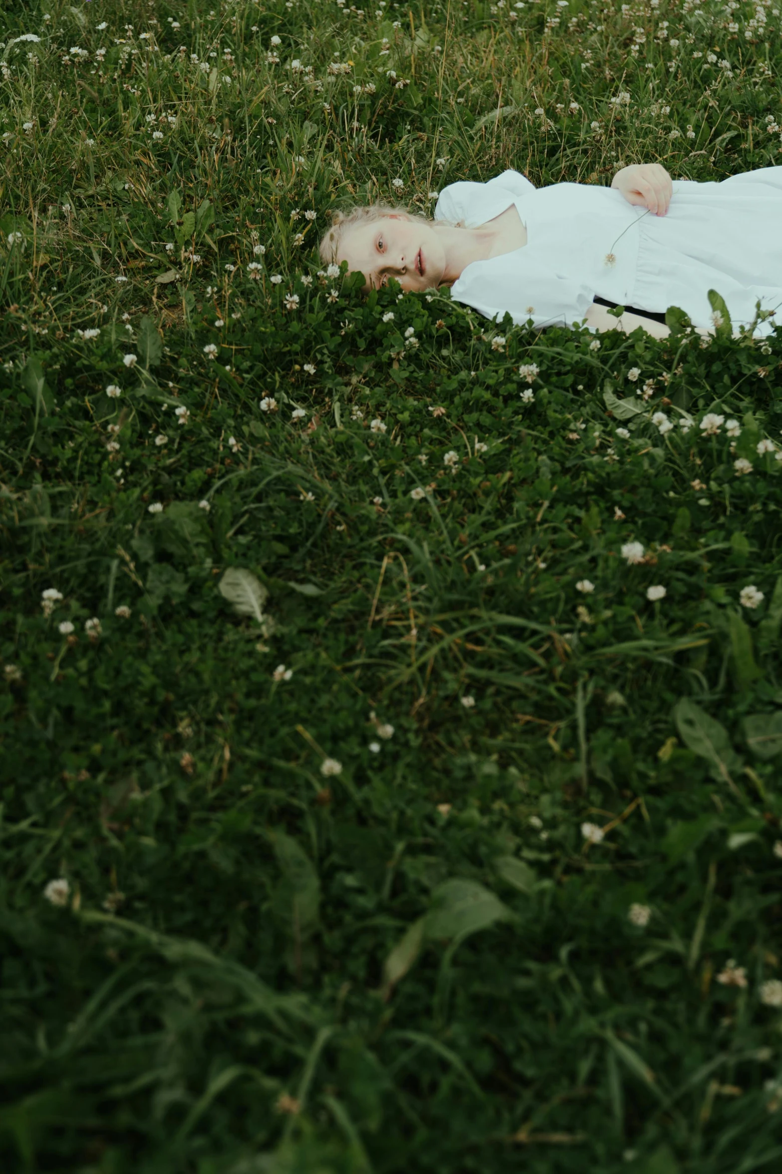 a baby laying on top of a lush green field, an album cover, by Attila Meszlenyi, unsplash, conceptual art, extremely pale white skin, ignant, ari aster, lawns