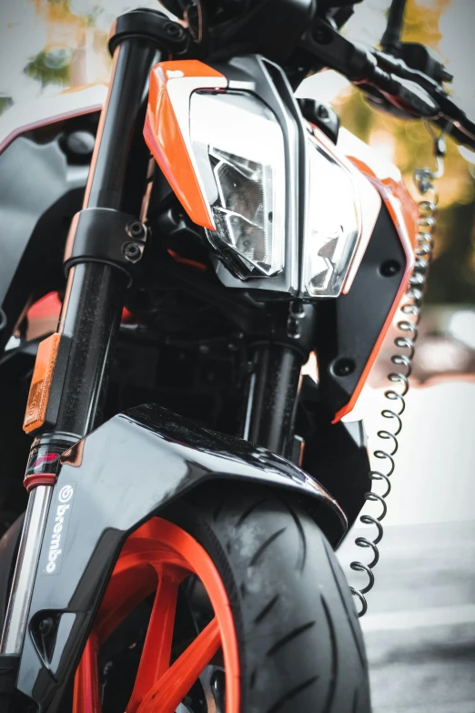 a close up of a motorcycle parked on a street, orange and black, profile image, front light, hydraulic features