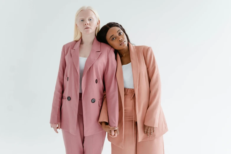 two women in pink suits standing next to each other, trending on pexels, aestheticism, lena oxton, mix of ethnicities and genders, one blonde and one brunette, wearing jacket