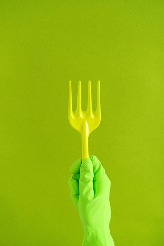 a person in a green glove holding a fork, by Andries Stock, plasticien, yellow, environment, instagram post, clean environment