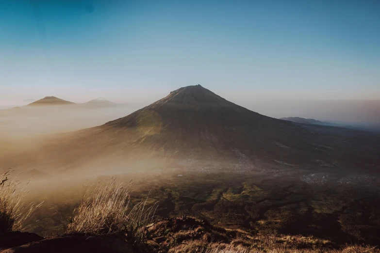 a person standing on top of a mountain, unsplash contest winner, sumatraism, mount doom, background image, dusty light, azores