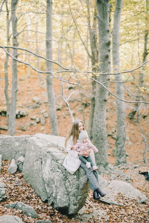 a woman sitting on a rock in the woods, with a kid, kodak portra, fall season, multiple stories