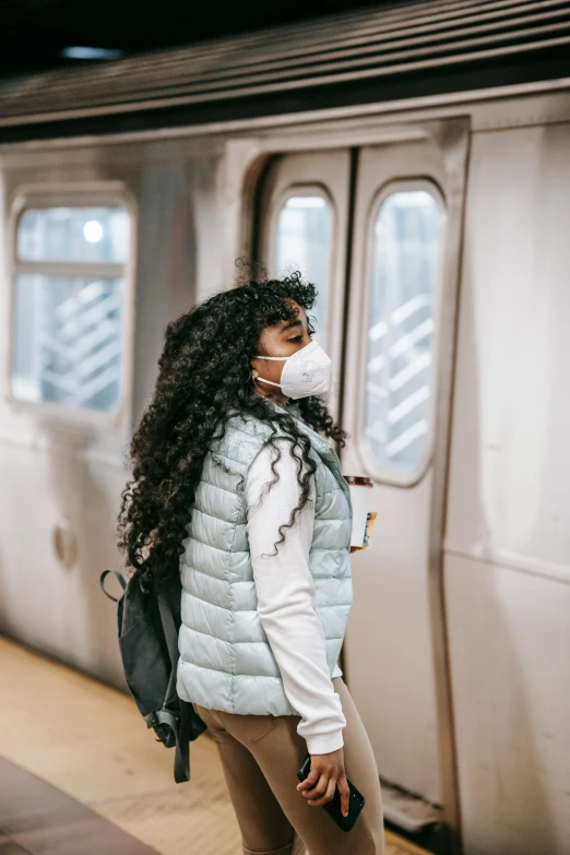 a woman standing in front of a subway train, trending on pexels, respirator, a black man with long curly hair, leaving a room, air pollution