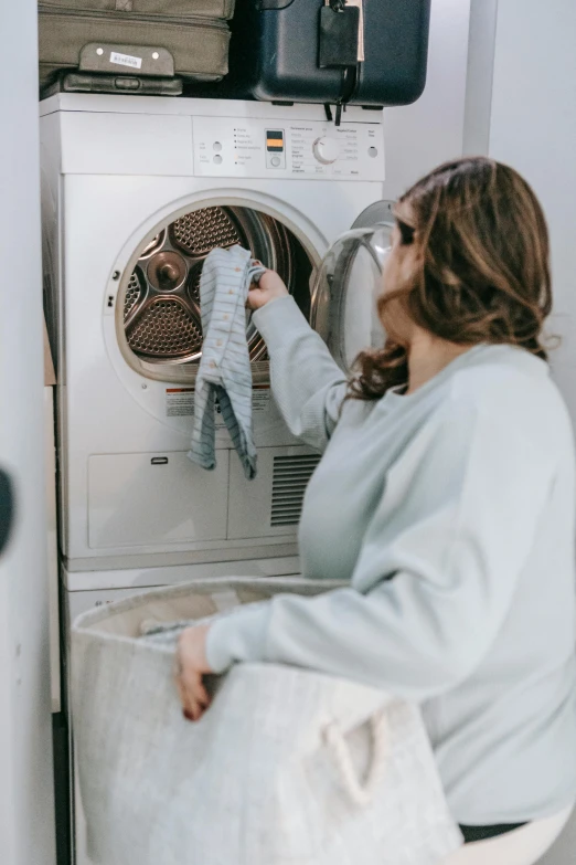 a woman sitting in front of a washing machine, pexels contest winner, grey robe, inspect in inventory image, profile image, australian