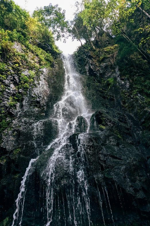 a waterfall in the middle of a lush green forest, an album cover, unsplash, reunion island, low-angle, multiple stories, bad photo