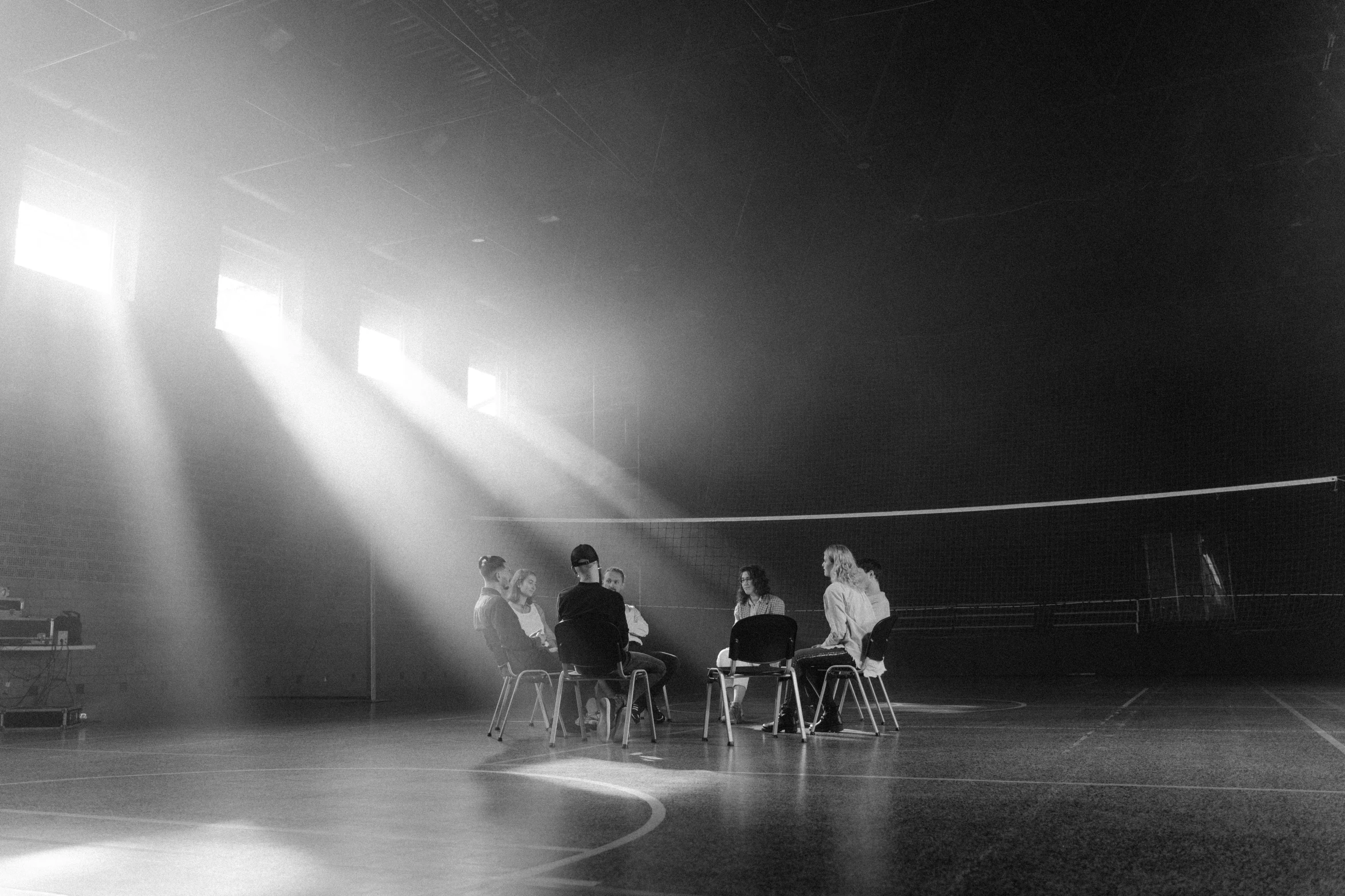 a group of people sitting around a table on a court, a black and white photo, by Maurycy Gottlieb, unsplash, light and space, ffffound, movie set, in the high school gym, under light
