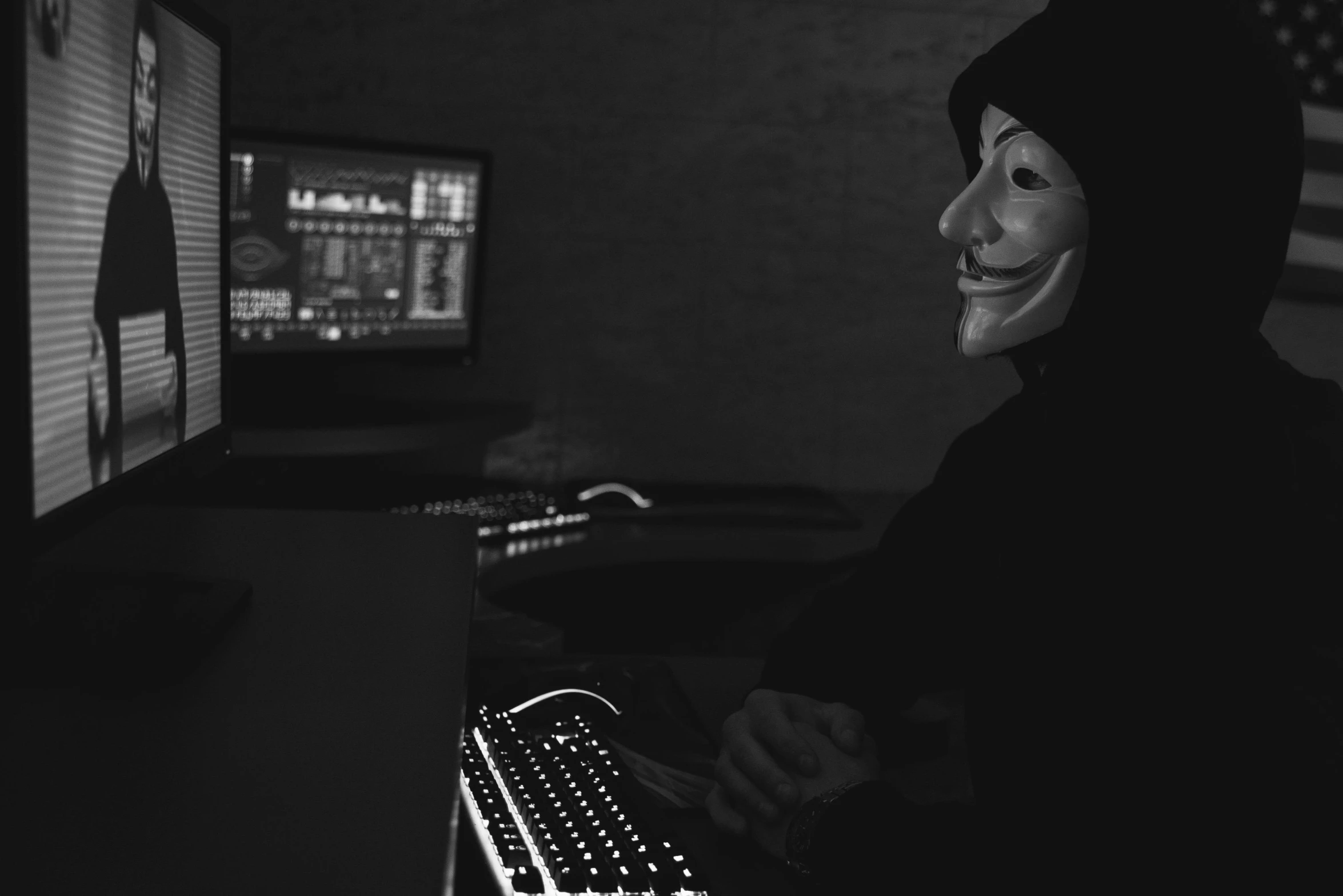 a man wearing a mask sitting in front of a computer, a black and white photo, pexels, computer art, wearing a dark hood, 15081959 21121991 01012000 4k, hashing, woman