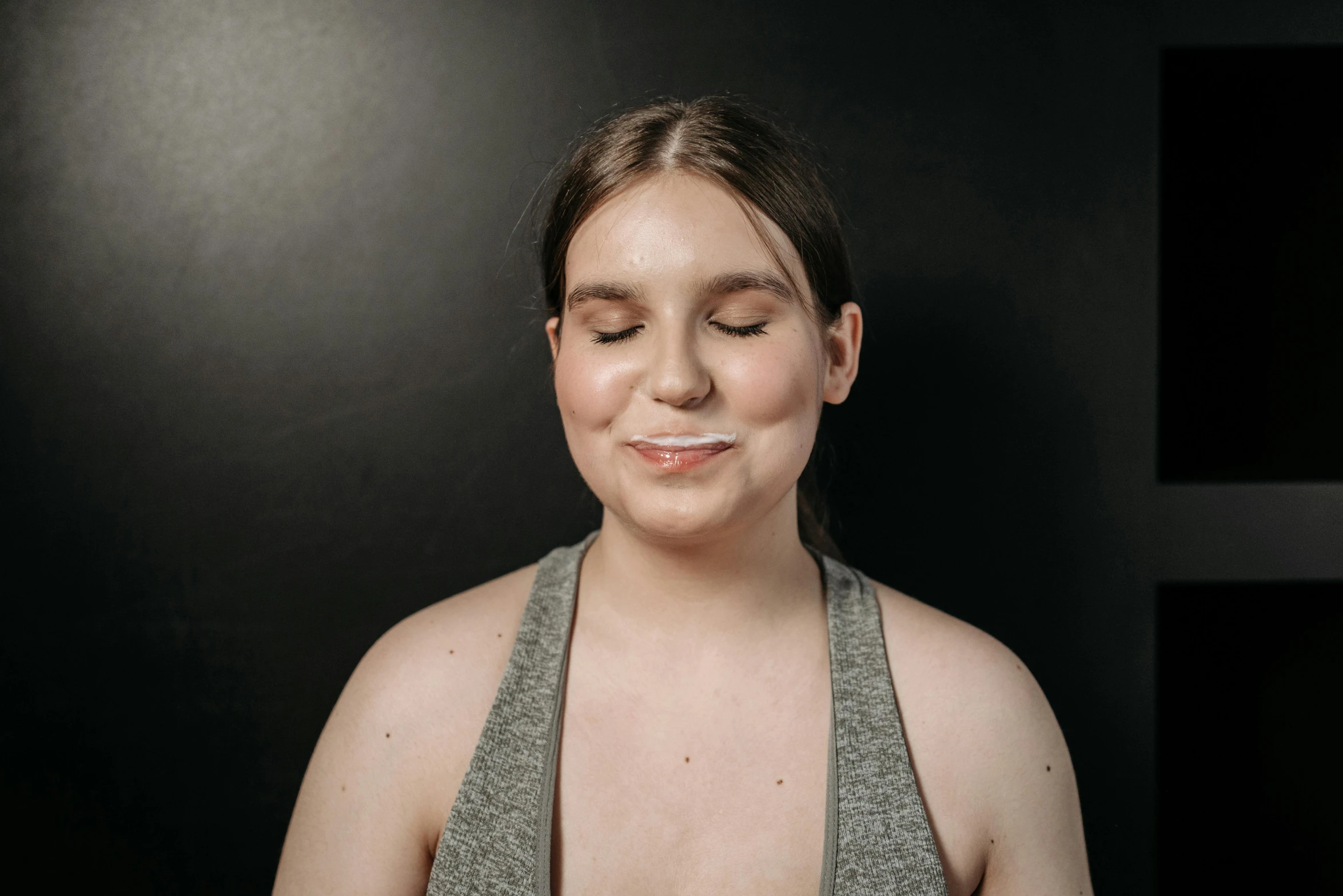 a close up of a person holding a plate of food, flat face, eyes closed, black backdrop, greta thunberg smiling