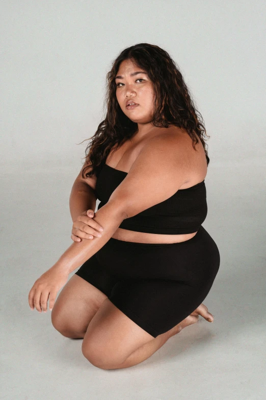 a woman in a black dress squatting on the ground, trending on pexels, extremely fat, wearing a tanktop and skirt, ad image, olive skinned