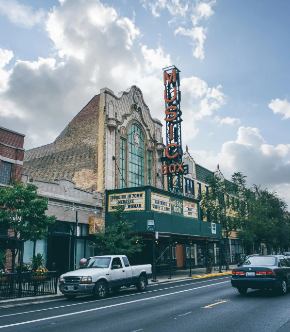 cars are driving down the street in front of a theater, by Morgan Russell, unsplash, art nouveau, chicago, “ iron bark, marilyn church h, a quaint