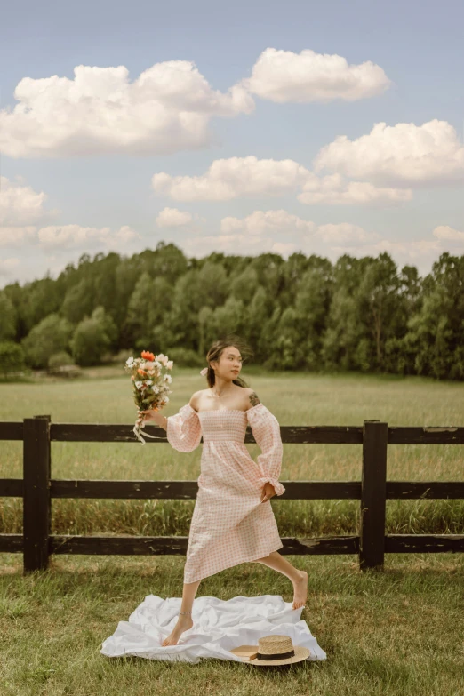 a woman standing in front of a fence holding a bouquet, inspired by Li Di, unsplash, renaissance, dressed in a pink dress, pastures, floating robes, young southern woman