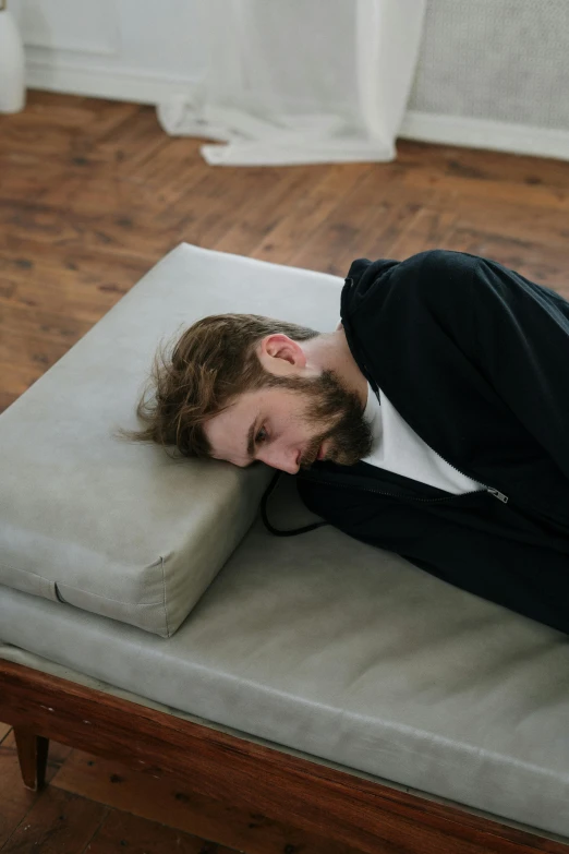 a man laying on a bed with his head on a pillow, by artist, trending on pexels, furniture overturned, half body photo, dimensional, squinting