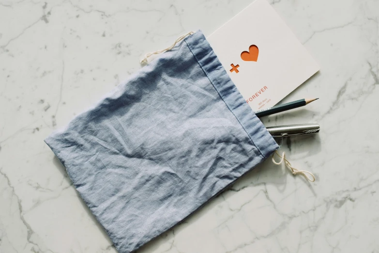 a bag of pencils sitting on top of a table, an album cover, by Christen Dalsgaard, unsplash, pale blue outfit, several hearts, linen canvas, surgical iv bag