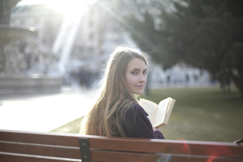 a woman sitting on a bench reading a book, a portrait, pexels contest winner, happening, girl with long hair, light glare, ((portrait)), medium head to shoulder shot