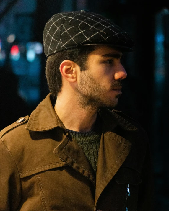 a man standing on a city street at night, a colorized photo, by Adam Rex, breton cap, masculine jawline, diego fernandez, brown jacket