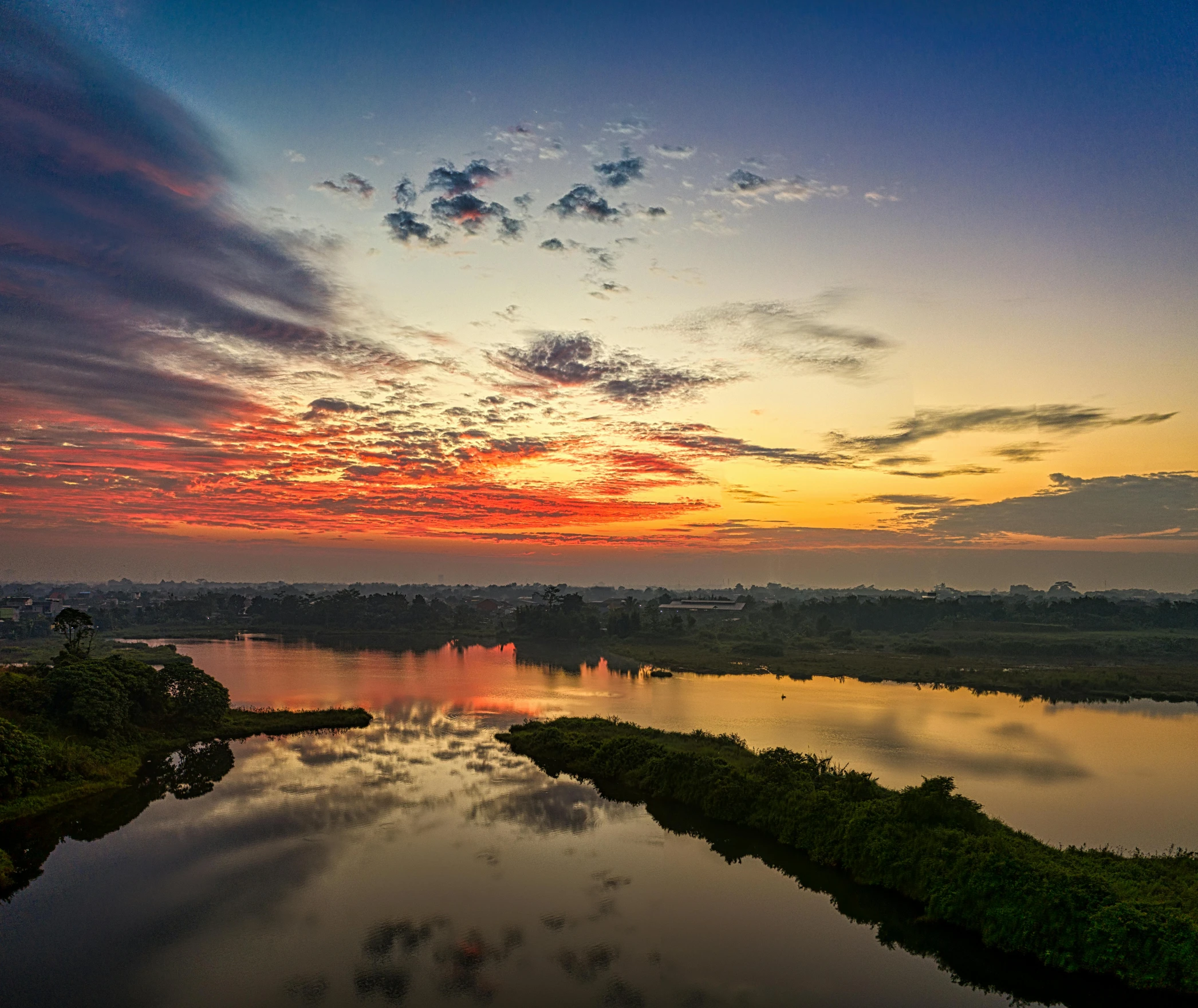 a large body of water sitting next to a lush green forest, orange and red sky, calcutta, cairo, fan favorite