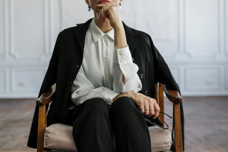 a woman sitting in a chair with her hand on her chin, trending on pexels, renaissance, business clothes, an elderly, wearing white silk, wearing black clothes