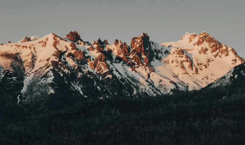 a mountain range with snow covered mountains in the background, by Andrei Kolkoutine, unsplash contest winner, warm light, tall spires, slightly pixelated, craggy