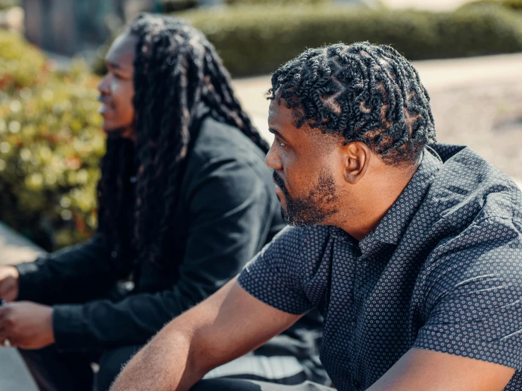 two men sitting next to each other on a bench, pexels contest winner, black arts movement, a black man with long curly hair, profile image, college, pictured from the shoulders up