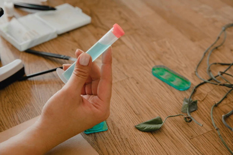 a person holding a toothbrush on top of a wooden table, experimenting in her science lab, scales made of jade, microchip leaves, modelling clay