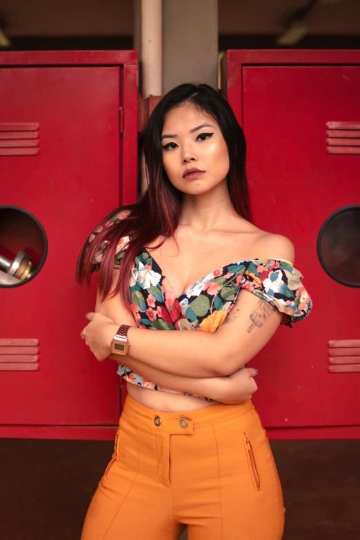 a woman standing in front of a red locker, an album cover, inspired by helen huang, trending on pexels, wearing yellow croptop, body covered in floral tattoos, attractive pose, pov photo