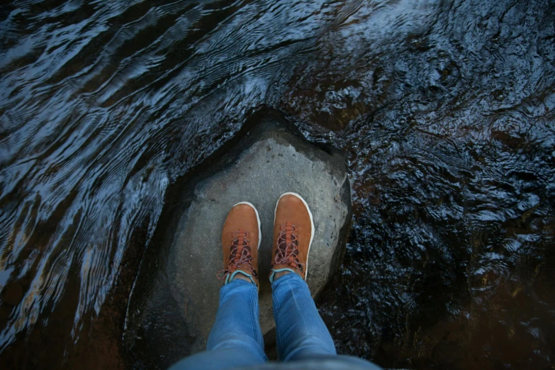 a person standing on a rock in the water, gum rubber outsole, trending photo, looking from slightly below, portrait photo