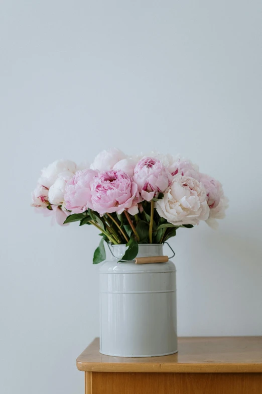 a white vase filled with pink flowers on top of a wooden table, pexels contest winner, peonies, white background and fill, on a gray background, with a soft