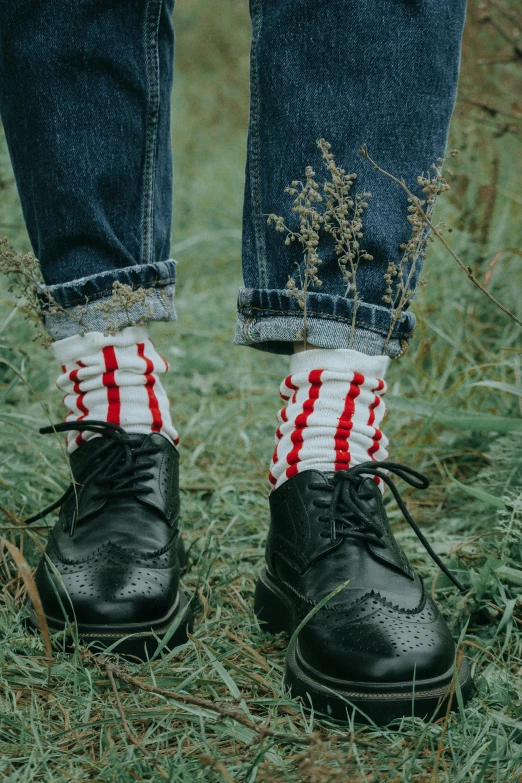 a person standing on top of a grass covered field, striped socks, accents of red, vintage inspired, college