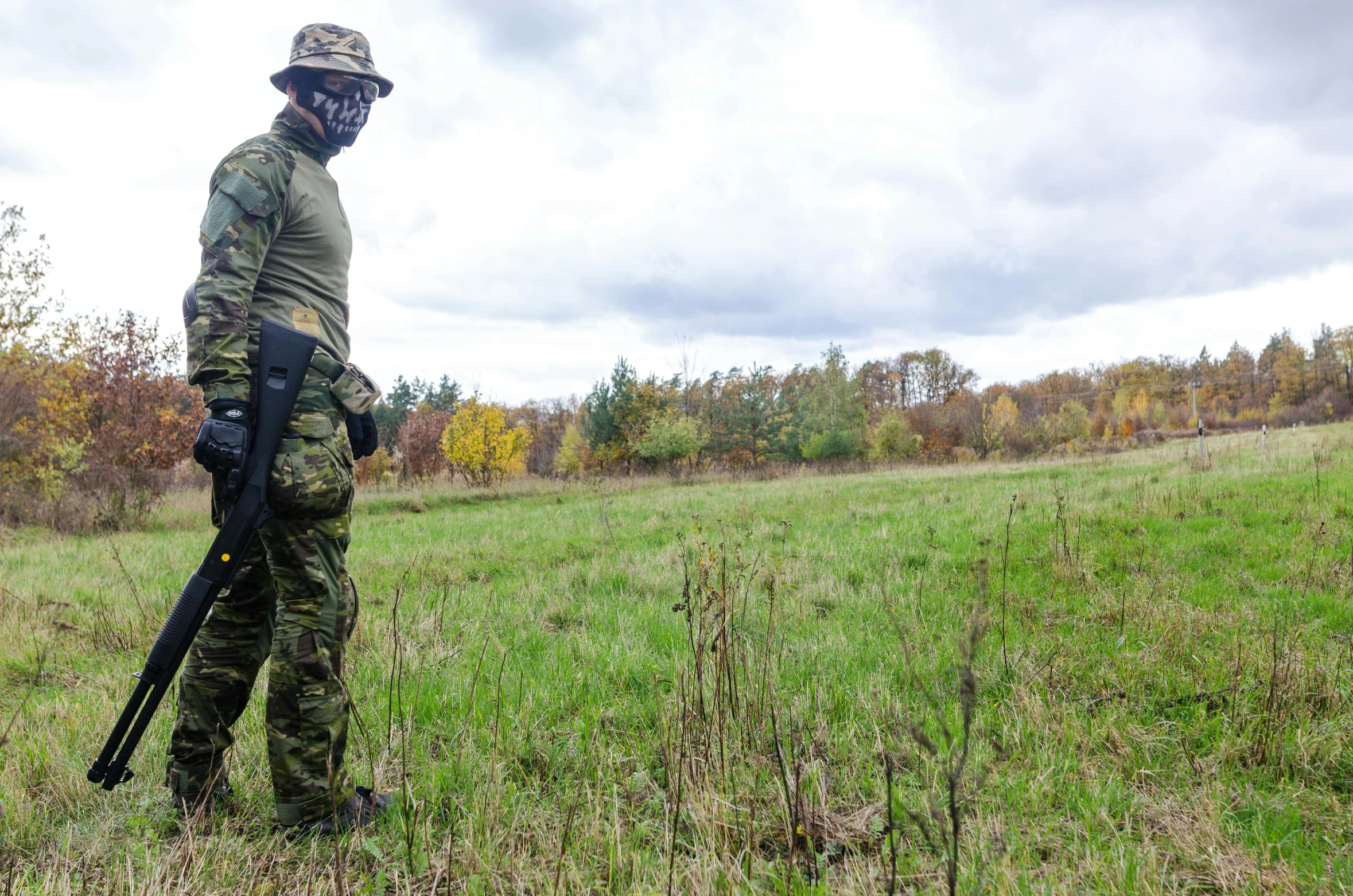 a man in camouflage holding a rifle in a field, by Adam Marczyński, tourist photo, fall season, area 3, operation