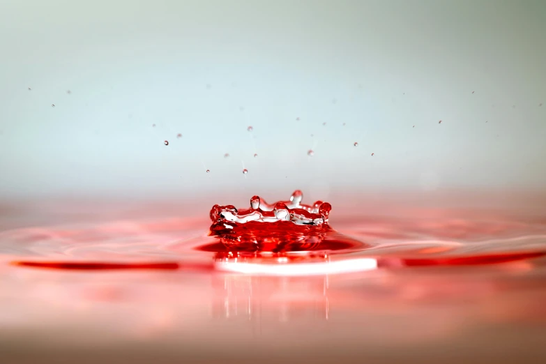 a red liquid drop falls into the water, a macro photograph, pexels, floating crown, low - level view, reds), on a pale background