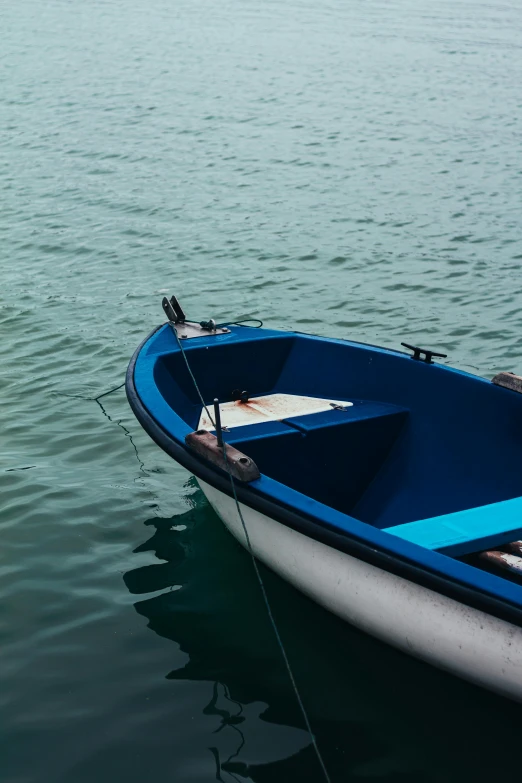 a blue and white boat sitting on top of a body of water, pexels contest winner, breton cap, dark dingy, serene colors, plain