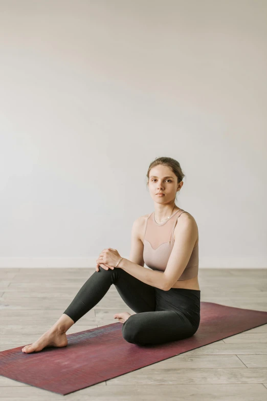 a woman sitting on a yoga mat in a white room, a picture, by Arabella Rankin, unsplash, default pose neutral expression, looking to the right, casey cooke, plain background