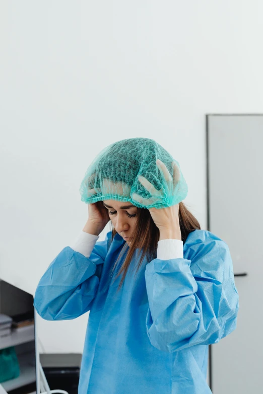 a woman in a hospital gown holding her head, trending on pexels, wearing her helmet, shy looking down, technical, thumbnail