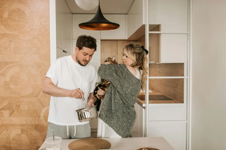 a man and woman standing in a kitchen preparing food, by Julia Pishtar, pexels contest winner, holding a cat, lachlan bailey, soup, gif